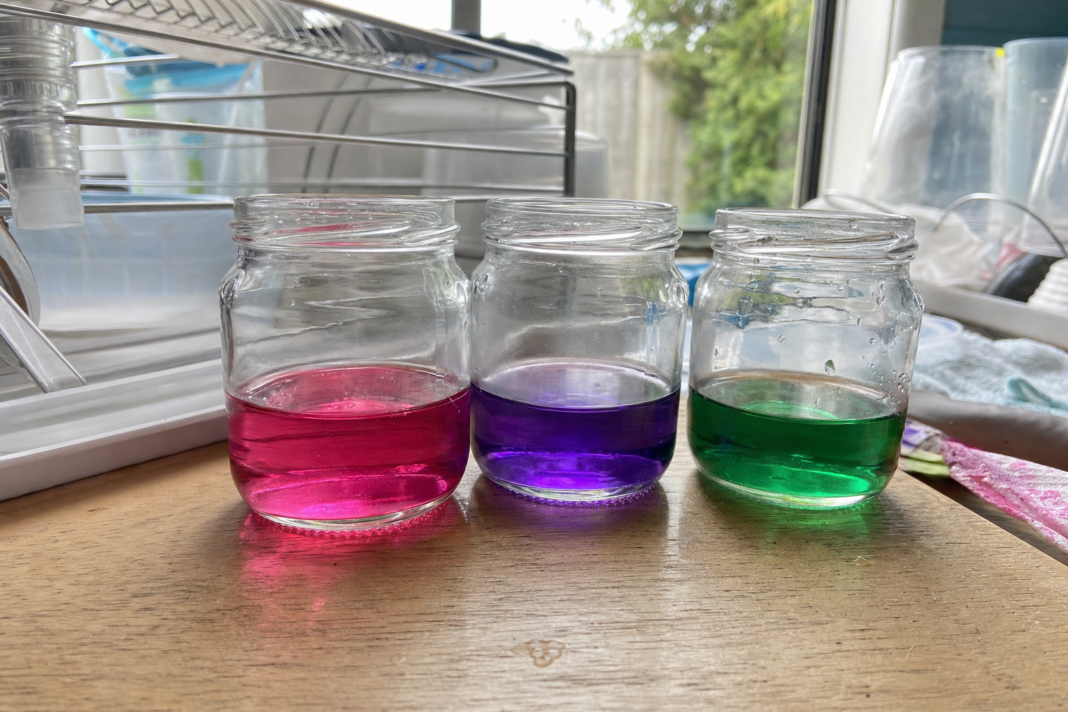 Three jars of brightly coloured cabbage indicator potions in pink, purple and green